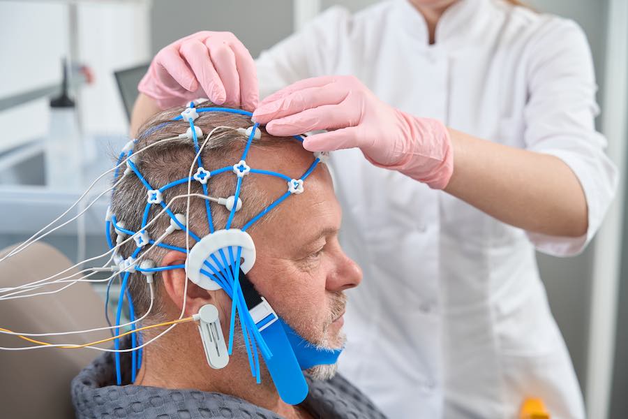 Diagnostician doctor attaches electrodes to the patient head, a man goes through a checkup in a medical center