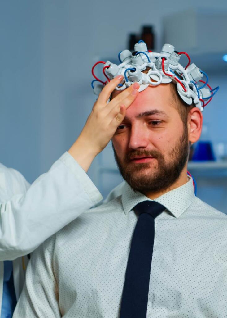 Neurologist doctor analysing brain of man and nervous system using brainwave scanning headset. Researcher using high tech developing neurological innovation monitoring side effects on monitor screen